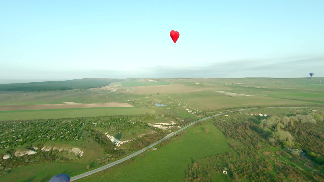 globo de aire caliente en forma de corazón sobre el paisaje panorámico del campo