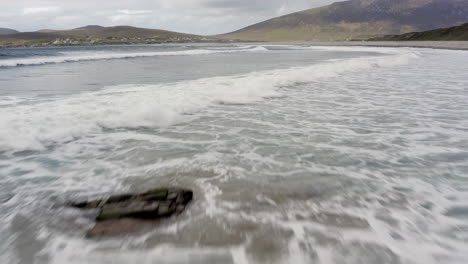 crashing waves spread white water froth along open ocean, aerial dolly, slow motion