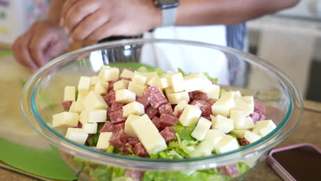 agregando queso provolone a una ensalada picada - serie de ensalada antipasto