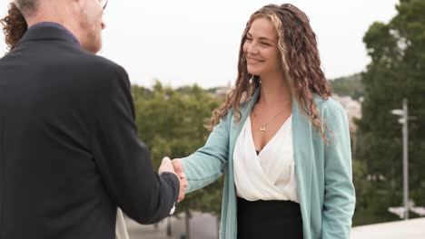 businesswoman shaking hands with partner outside during daytime