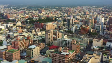 Aerial-drone-flyover-capturing-the-sunset-downtown-cityscape-of-Douliu-city,-Yunlin-county,-the-countryside-of-Taiwan