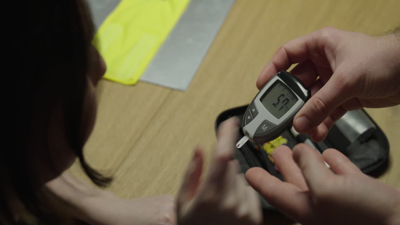 Close up of two people reviewing a blood glucose reading on a digital glucometer, illustrating diabetes management, medical consultation, and health monitoring discussion