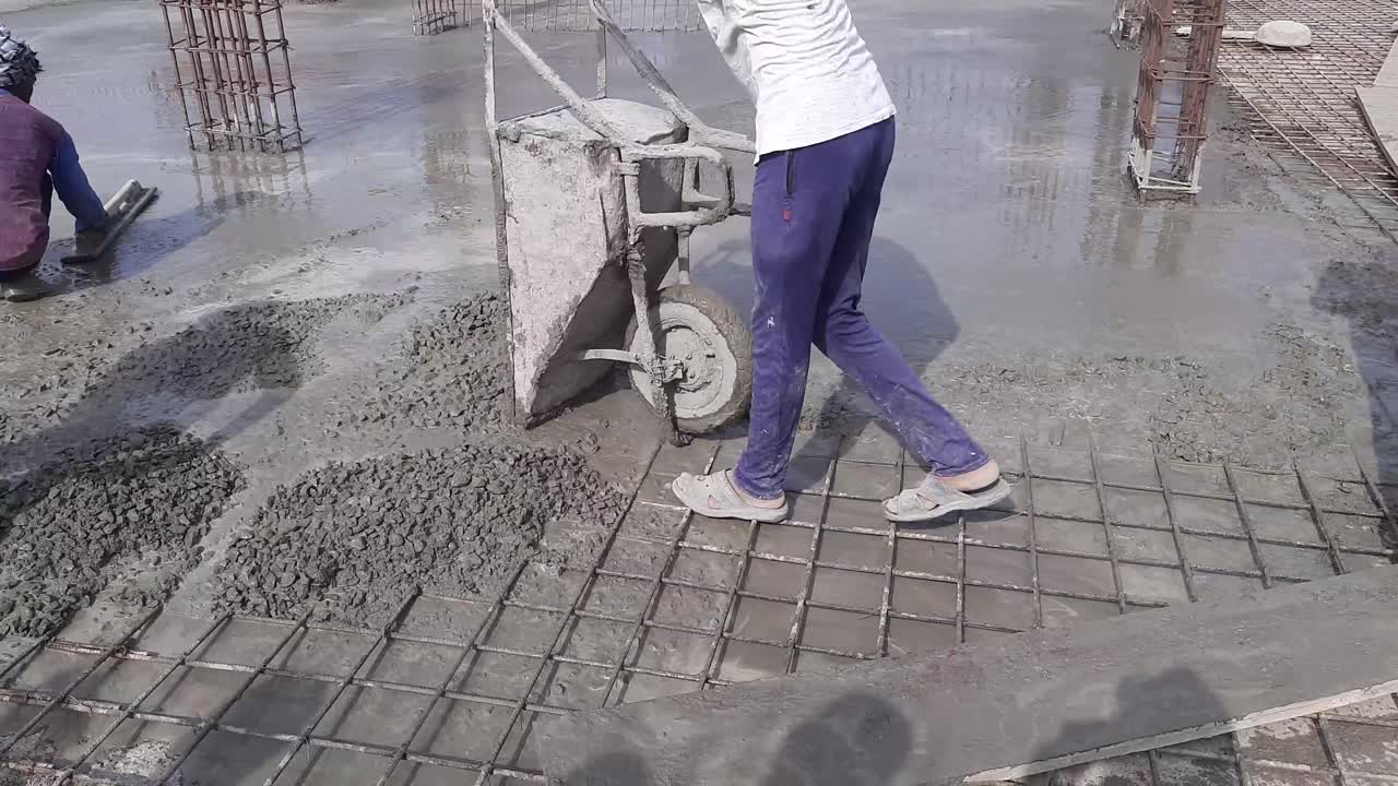 Construction trolley or wheelbarrow with sand and cement prepared by workers for concrete at the construction site