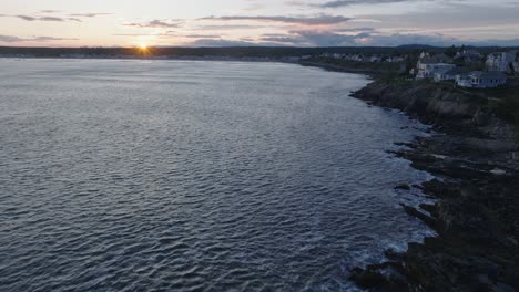 aerial drone shot of york beach maine flying over cape neddick nubble lighthouse into the sunset