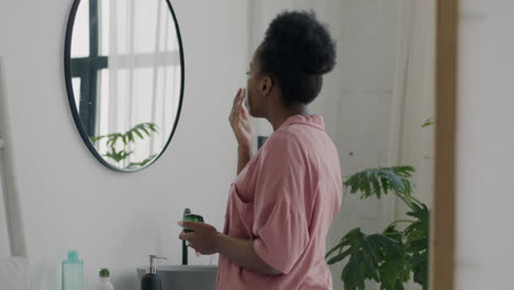 mujer aplicando crema facial en el baño