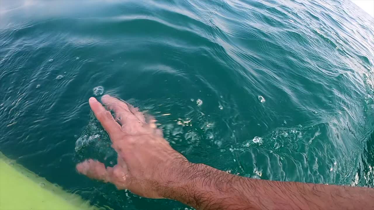 mano tocando el océano mientras navega en un kayak