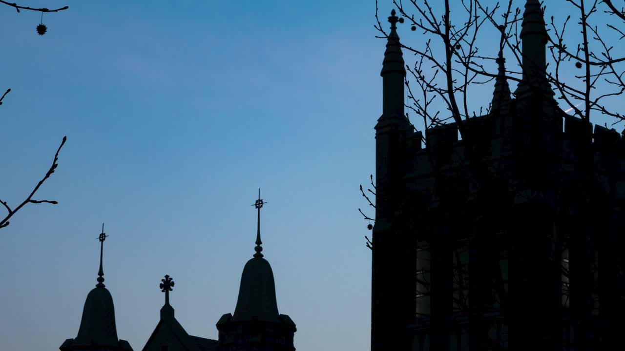Timelapse af smuk solnedgangsfarvet himmel og skyer med kirkesilhuet i forgrunden og fly med kondensstriber, der flyver igennem.