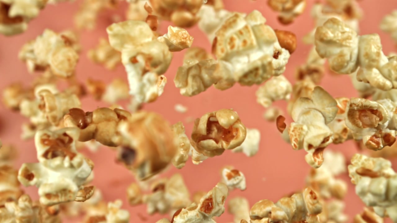 Delicious Popcorn Falling in Super Slow Motion Against Pink Background