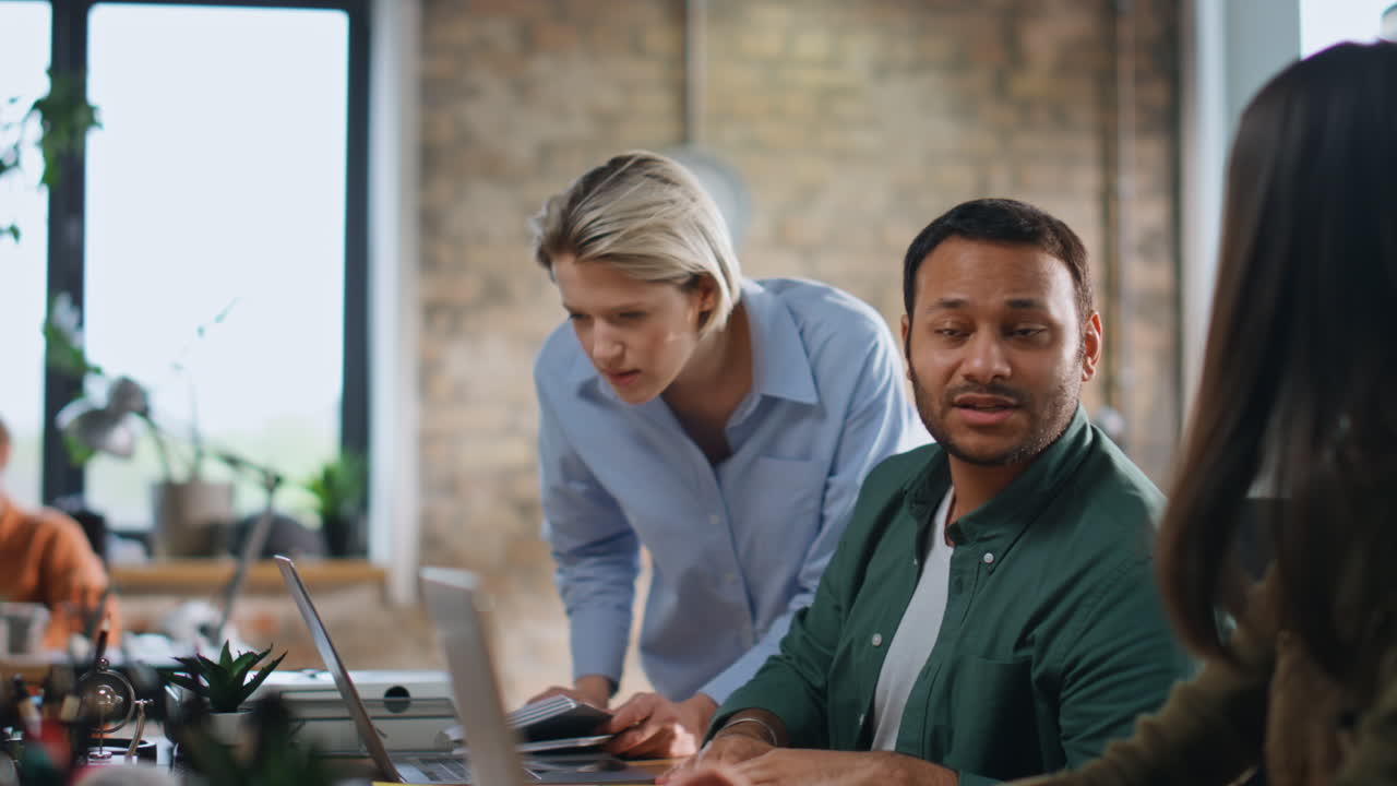 Woman supervisor checking coworkers working in workplace with laptops close up.