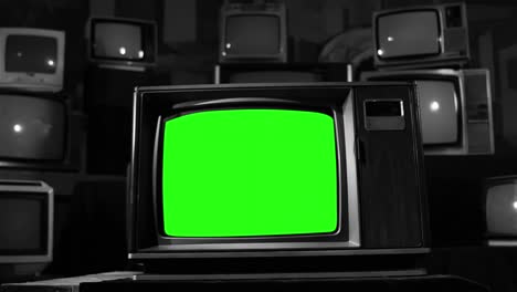많은 레트로 tv 세트 가운데 녹색 화면을 가진 빈티지 텔레비전 세트. 검은색과 색 톤. dolly out. 4k 해상도.