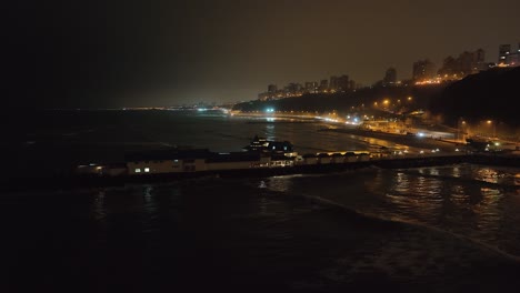 aerial: night pier restaurant, highway traffic below lima peru cliffs