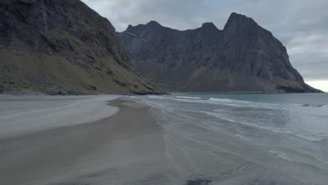 Vista-Aérea-De-Drones-Dando-Vueltas-A-Baja-Altura-Sobre-Una-Playa-Tranquila,-En-Kvalvika-Nublada,-En-Lofoten,-Noruega