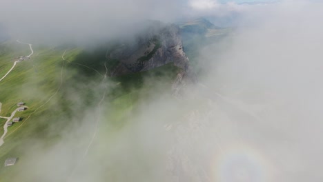 aerial footage of seceda’s rugged cliffs slowly emerging from dense clouds, 4k