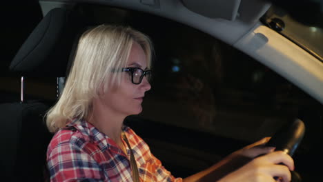 Eine-Frau-Mit-Brille-Fährt-Ein-Auto-Durch-Die-Nachtstadt-4k-Video