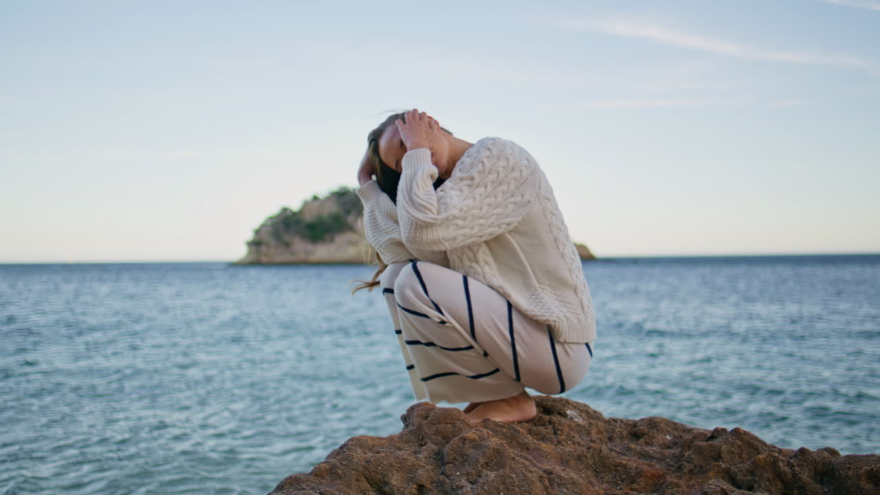 model posing seascape crouching on coastal rock. Woman enjoying ocean