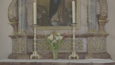 baroque altar of the virgin mary with candles in a church, camera pan from bottom to top