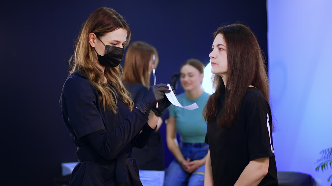 Beauty salon with clients and professionals. Eyebrow master stands in front of a client preparing materials.
