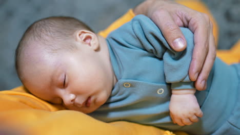 beautiful small child sleeping tightly in father's arms. cute baby boy in blue suit having sleep. close up.