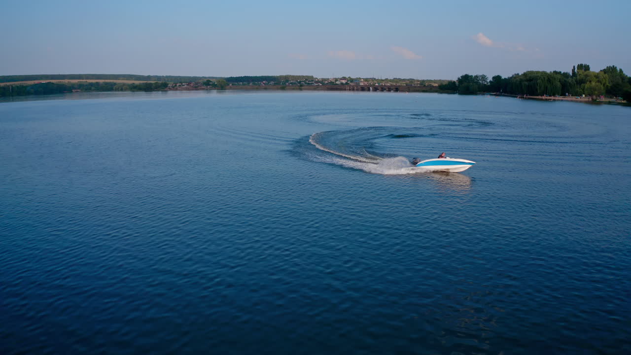 Speed boat sailing along river. Aerial shot of cruising speed boat on calm river