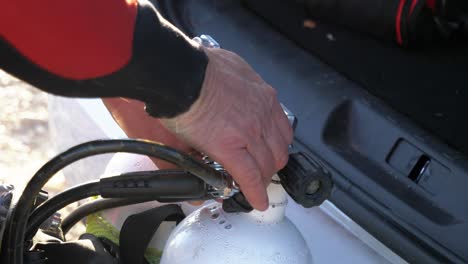 a diver screws his oxygen mask onto his tank