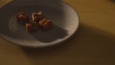 close up of person picking up and eating chocolate brownies from plate