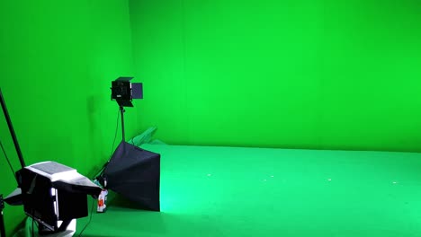 A-filming-studio-simple-setup-with-green-screen-walls-and-floor,-lighting-and-softbox-equipment-ready-for-a-video-shoot-session