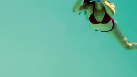 pretty brunette diving into swimming pool wearing snorkel