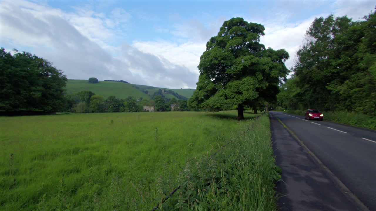 Scenic Countryside Road with Lush Green Fields and Rolling Hills