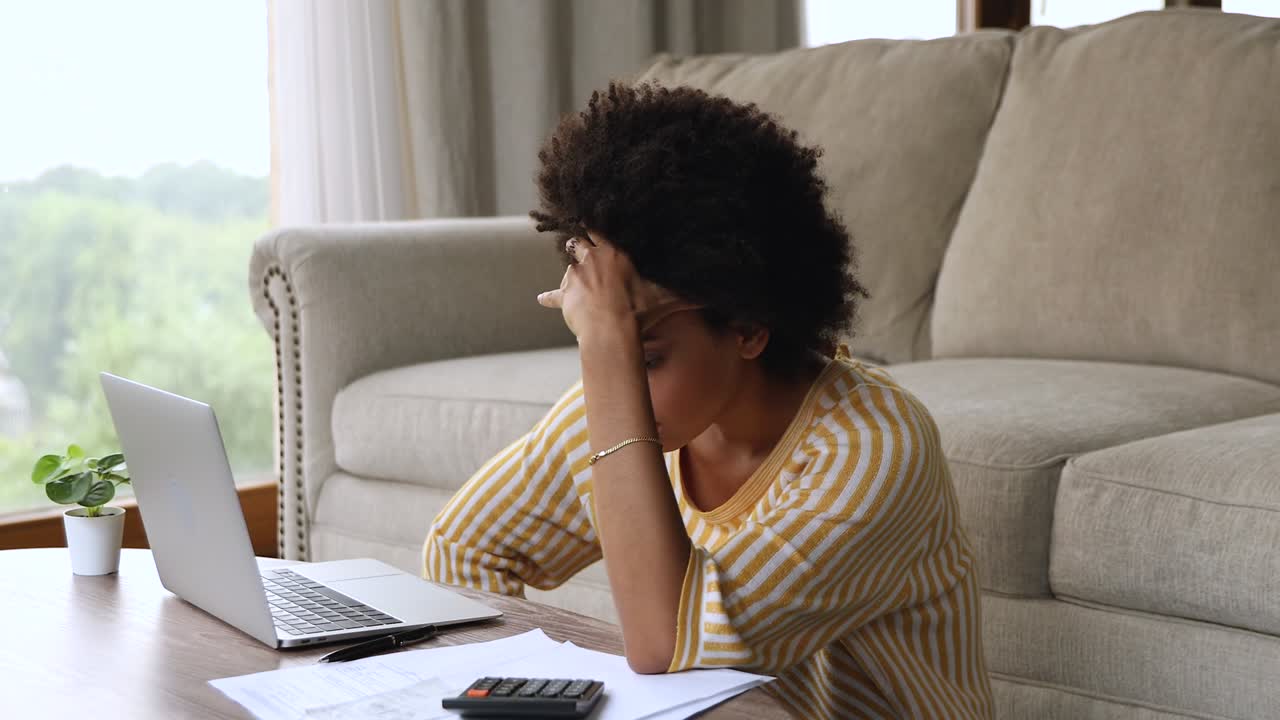 mujer negra confundida calcular los gastos abrazar la cabeza pensar en la bancarrota