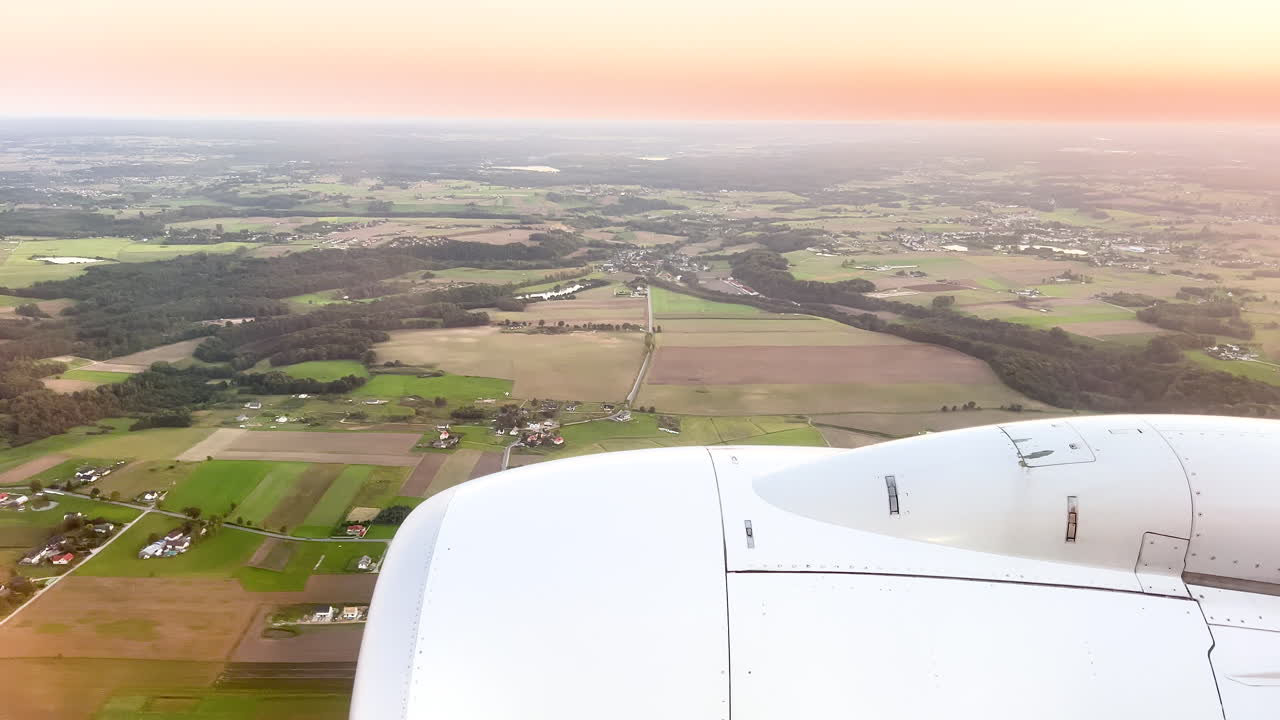 Golden sunset from an airplane window, with the aircraft's engine over a pastoral landscape
