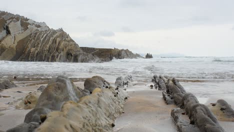 flysch layers and ocean waves crashing on sharp pieces, itzurun beach