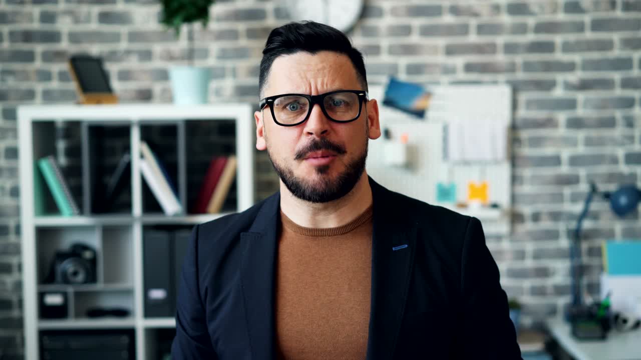 retrato de un hombre barbudo enojado gritando y apuntando a la cámara en la oficina