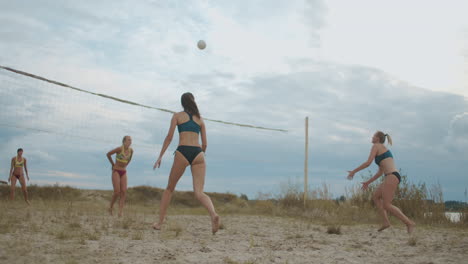 women are playing beach volleyball at summer vacation slow motion shot of jumping and running athletes on sandy court