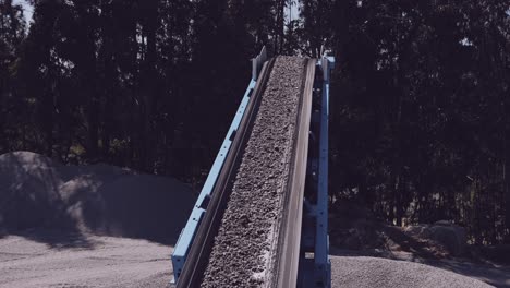 Conveyor-belt-transporting-crushed-stone-in-a-quarry,-surrounded-by-nature