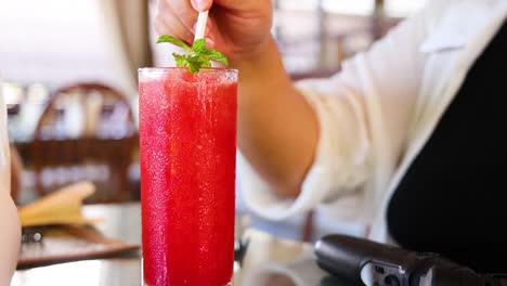 una persona prepara un vibrante jugo de sandía en un acogedor café tailandés, destacando los ingredientes frescos y una atmósfera relajada