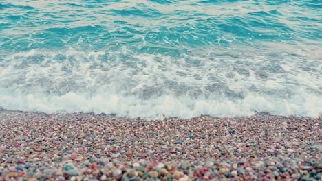 Stunning-4k-video-of-a-rocky-beach-with-foamy-blue-waves-and-multiple-colour-stones