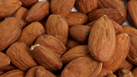 almonds cascade onto a white surface, creating a textured pile. warm lighting highlights the nuts' natural brown tones