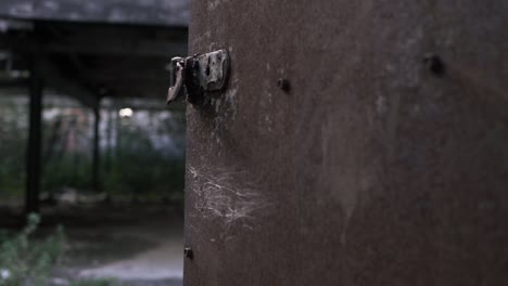 view of derelict building through rusty old door close up panning shot