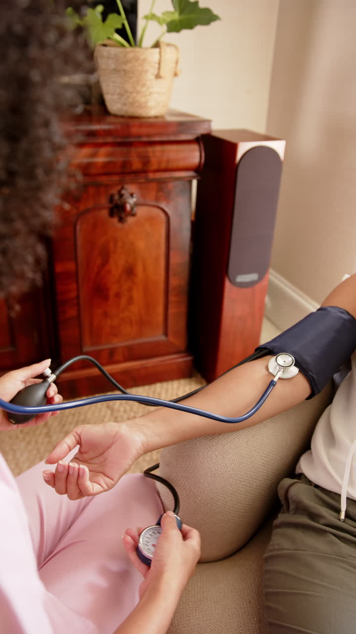 Vertical video: Using sphygmomanometer, healthcare professional checking blood pressure on patient's