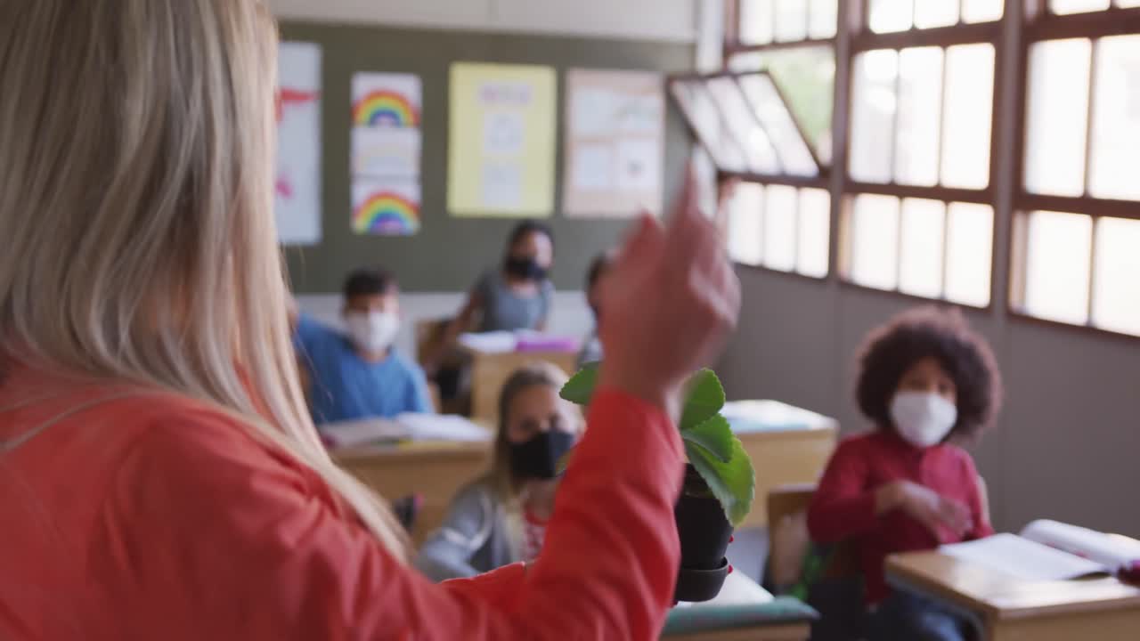 maestra mostrando una maceta de plantas a un grupo de niños en clase en la escuela