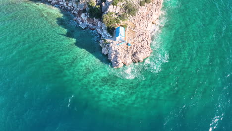 drone footage over a small greek orthodox church on the rock next to the sea