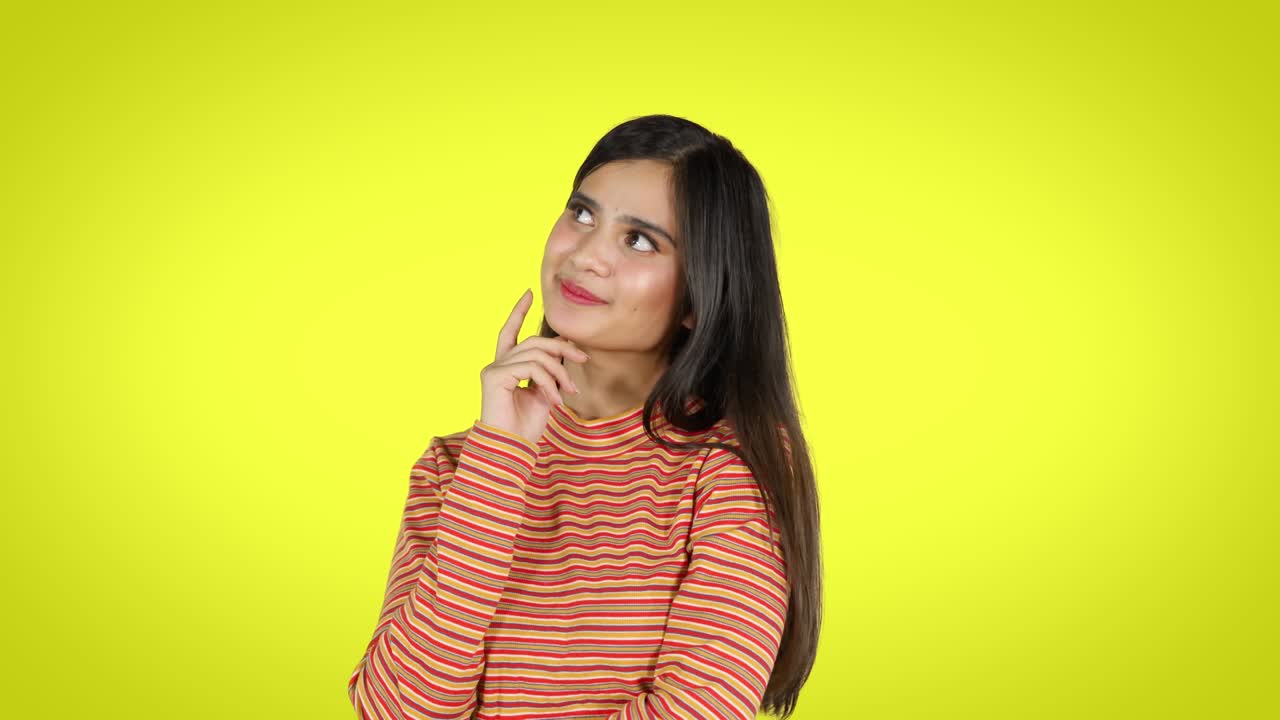 Attractive young woman daydreaming in studio