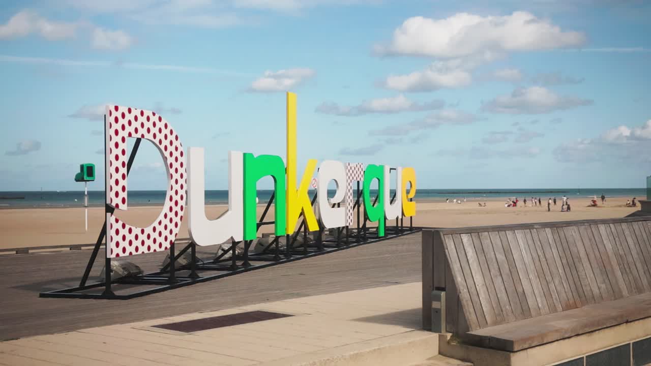 Colorful Dunkerque beach sign with sandy coast and sea in the background