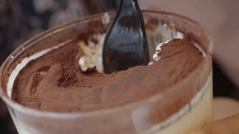 close-up of tiramisu dessert in a container with a spoon