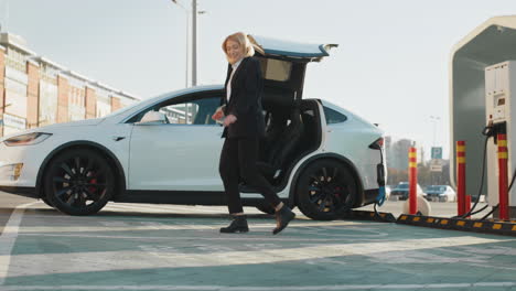 mujer de negocios cargando un vehículo eléctrico