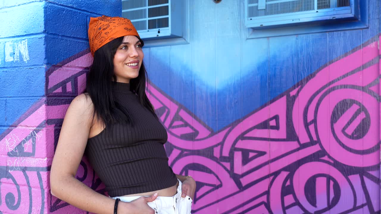 Mujer joven sonriendo y posando frente a un vibrante muro de grafitis