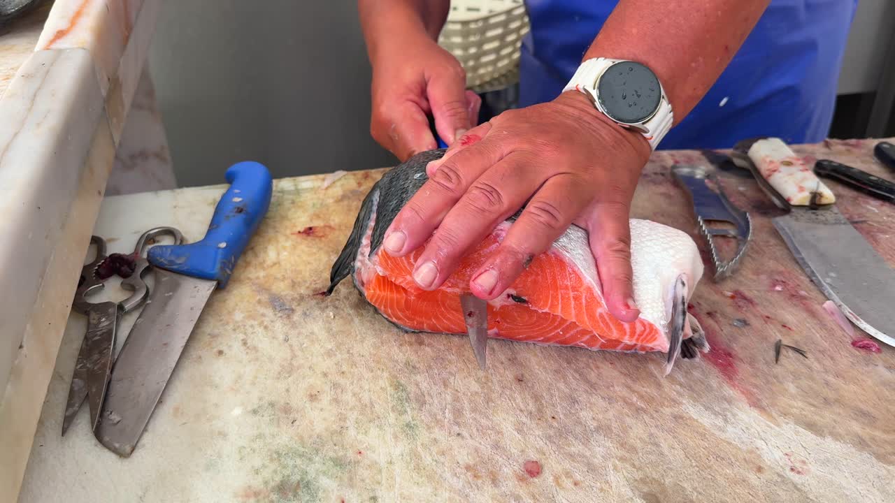 Close-up of hands filleting fresh salmon on a cutting board