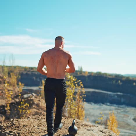 sportsman is drinking water from a bottle outdoors. muscular shirtless bodybuilder drinks water after hard training on the nature background.