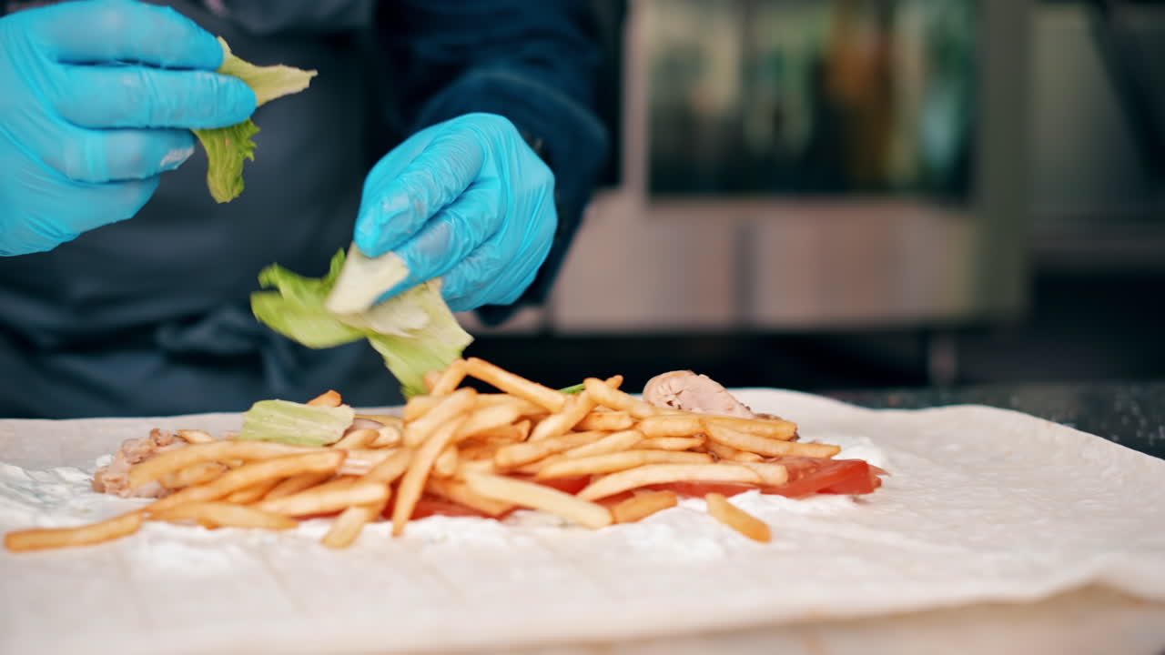 Cook adding salad into a wrap in a food truck