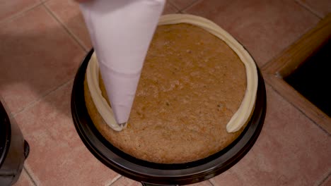 putting frosting on carrot cake